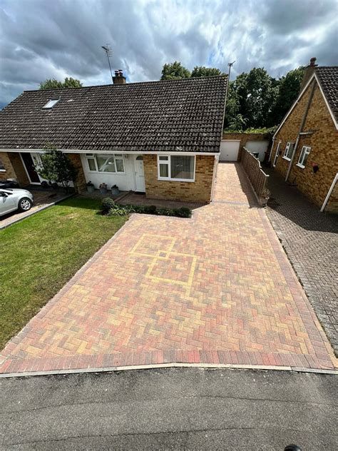 High-angle view of a residential property with a large, freshly cleaned brick-paved driveway with decorative patterns